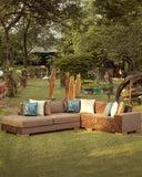 Brown sectional sofa with decorative pillows on a grassy outdoor area