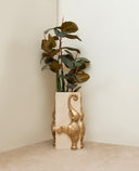 Decorative vase with a plant in it, featuring an elephant design on a plain background