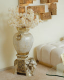 Decorative vase with elephant and flowers on a stand in a room setting.