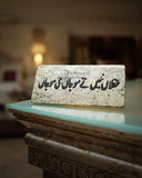 Decorative stone plaque with urdu text on a table