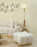 Living room with a white sofa, ottoman, and decorative lamp against a beige wall.