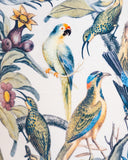 A close-up of a fabric or wallpaper pattern featuring detailed illustrations of tropical birds, parrots, and flowers on a light cream background.