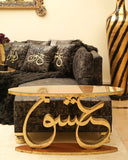 Living room with a gray sofa, decorative pillows, and a coffee table with ishq calligraphy.