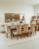 Dining room with a wooden table and beige chairs, large mirror on the wall, and decorative elements.