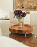 Wooden side table with a vase of purple flowers in a living room setting