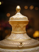 Decorative gold and white container with intricate designs on a blurred background
