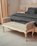 A classic French-style upholstered bench with a cream velvet seat and gold-trimmed cabriole legs, positioned at the foot of a bed in a luxury bedroom.