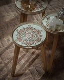Three small round tables with decorative tops on a patterned floor.