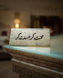 Decorative stone slab with urdu calligraphy on a table