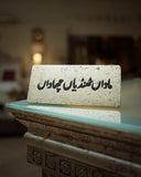 Decorative stone plaque with urdu text on a table