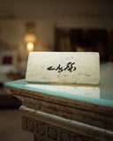 Decorative stone block with urdu text on a reflective surface