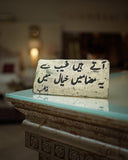 Decorative stone with urdu text on a reflective surface