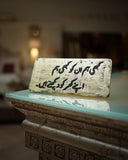 Decorative stone with urdu text on a reflective surface