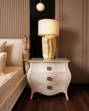 Neatly arranged bedroom with a nightstand, lamp, and decorative items.