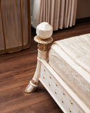 Close-up of a decorative bed post with intricate design on a wooden floor.